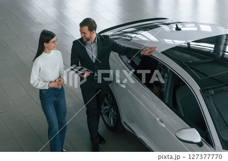 Top view. Man is showing the new automobile to the woman customer in the car dealership Top view. Man is showing the new automobile to the woman customer in the car dealership 127377770
