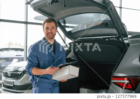 With box and notepad. Man in blue uniform is working in the car service 127377969