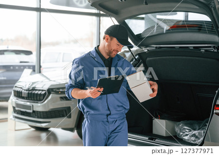 With box and notepad. Man in blue uniform is working in the car service 127377971