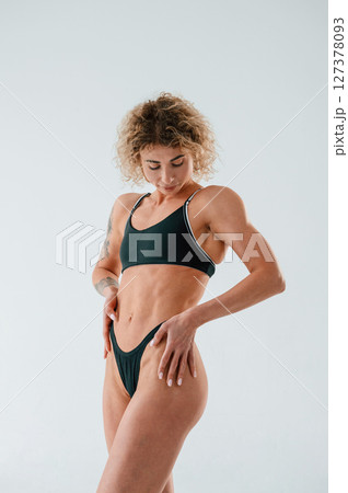 Standing and posing. Young caucasian woman with athletic body shape is indoors at daytime 127378093