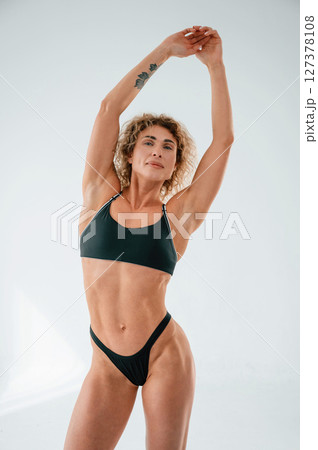 Standing with hands up. Young caucasian woman with athletic body shape is indoors at daytime Standing with hands up. Young caucasian woman with athletic body shape is indoors at daytime 127378108