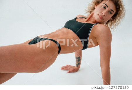 On the hands and legs. On the floor. Young caucasian woman with athletic body shape is indoors at daytime 127378129