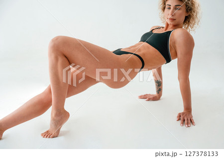 On the hands and legs. On the floor. Young caucasian woman with athletic body shape is indoors at daytime 127378133