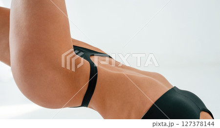 Close up view of hips and body. Young caucasian woman with athletic body shape is indoors at daytime 127378144