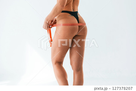 Back is being measuring by the tape. Young caucasian woman with athletic body shape is indoors at daytime 127378207