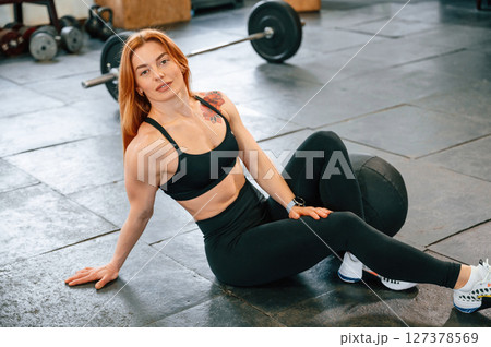 Sitting on the floor. Beautiful strong woman is in the gym Sitting on the floor. Beautiful strong woman is in the gym 127378569
