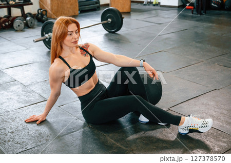 Sitting on the floor. Beautiful strong woman is in the gym 127378570
