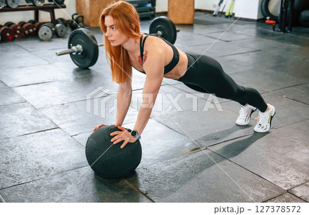 Doing push ups by using soft ball. Beautiful strong woman is in the gym Doing push ups by using soft ball. Beautiful strong woman is in the gym 127378572