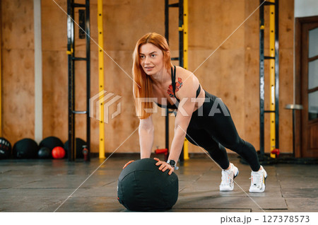 Doing push ups by using soft ball. Beautiful strong woman is in the gym 127378573