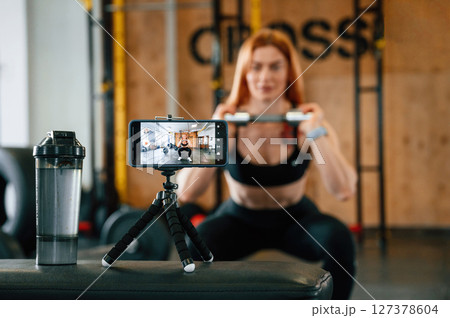 Shooting video by smartphone. Doing exercises. Beautiful strong woman is in the gym 127378604