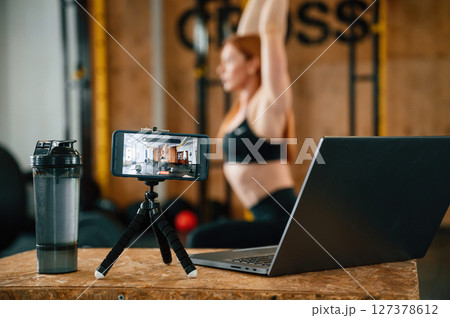 Shooting video by smartphone. Doing exercises. Beautiful strong woman is in the gym Shooting video by smartphone. Doing exercises. Beautiful strong woman is in the gym 127378612