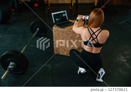View from the back. Shooting video by smartphone. Beautiful strong woman is in the gym View from the back. Shooting video by smartphone. Beautiful strong woman is in the gym 127378621