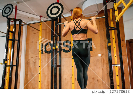 Pull-up exercise. Beautiful strong woman is in the gym Pull-up exercise. Beautiful strong woman is in the gym 127378638