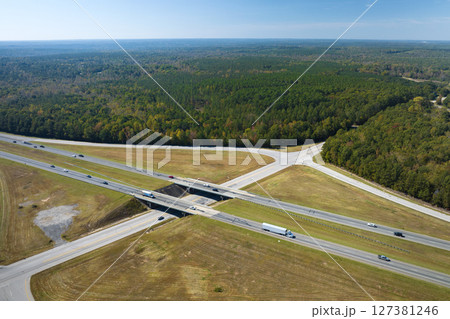 View from above of busy american highway with fast moving traffic between woods. Interstate transportation concept View from above of busy american highway with fast moving traffic between woods. Interstate transportation concept 127381246