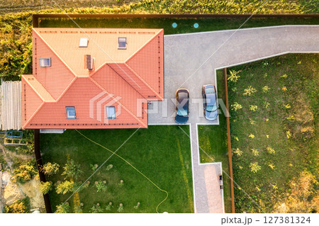 Top down aerial view of a private house with red tiled roof and spacious yard with parked two new cars. Top down aerial view of a private house with red tiled roof and spacious yard with parked two new cars. 127381324