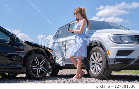 Stressed driver talking on sellphone on roadside near her smashed vehicle calling for emergency service help after car accident. Road safety and insurance concept Stressed driver talking on sellphone on roadside near her smashed vehicle calling for emergency service help after car accident. Road safety and insurance concept 127381336