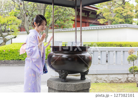 神社の常香炉で煙を浴びる和装の若い日本人女性 127382101