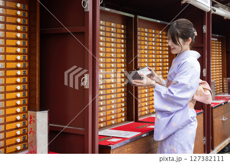 神社でおみくじを引く和装の若い日本人女性 127382111