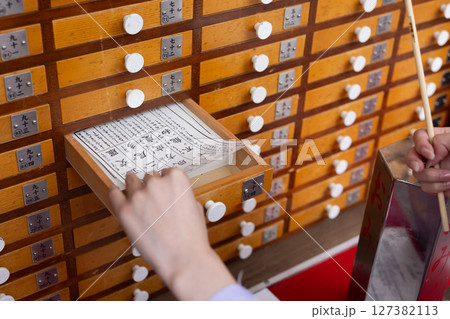 神社でおみくじを引く和装の若い日本人女性 127382113