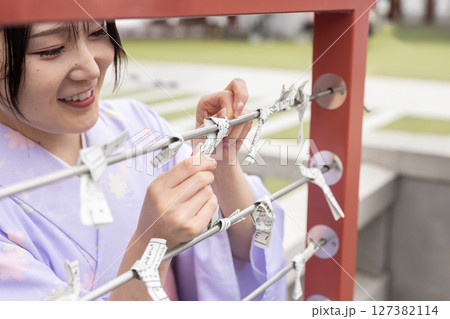 神社でおみくじを引く和装の若い日本人女性 神社でおみくじを引く和装の若い日本人女性 127382114