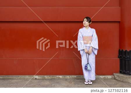 神社の朱色の壁の前に立つ和装の日本人女性 神社の朱色の壁の前に立つ和装の日本人女性 127382116