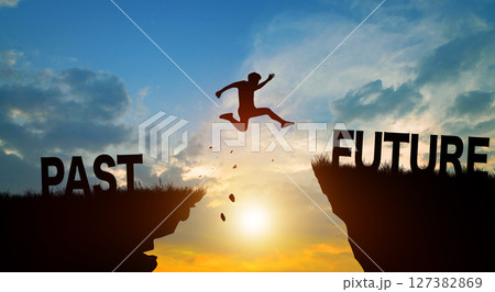 Silhouette man jumping from PAST to FUTURE wording on cliffs with cloud sky and sunrise. Go ahead and Keep go on to success Concept. Silhouette man jumping from PAST to FUTURE wording on cliffs with cloud sky and sunrise. Go ahead and Keep go on to success Concept. 127382869