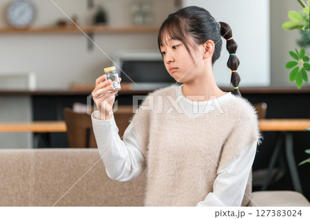 薬の瓶を持って悩む小学生,中学生の女の子 薬の瓶を持って悩む小学生,中学生の女の子 127383024