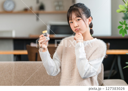 薬の瓶を持って悩む小学生,中学生の女の子 127383026