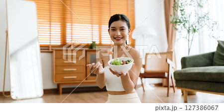 Healthy Asian Woman Enjoying Fresh Salad at Home After Yoga Workout Healthy Asian Woman Enjoying Fresh Salad at Home After Yoga Workout 127386067
