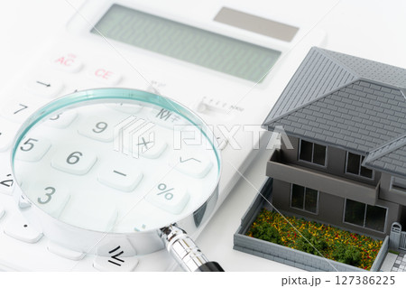 電卓と虫眼鏡とミニチュアの一戸建て住宅 127386225