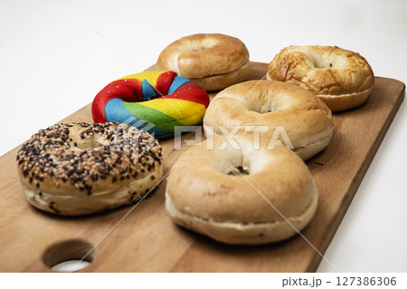 Closeup view of a collection of bagel breads with various kinds on a wooden board isolated over a white background Closeup view of a collection of bagel breads with various kinds on a wooden board isolated over a white background 127386306