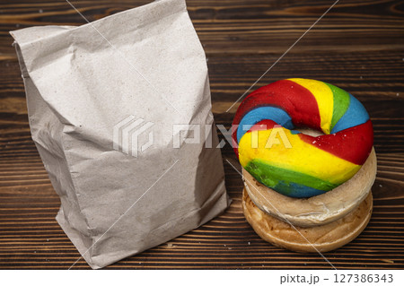 Closeup view of a pile of a collection of bagel breads with various kinds and a brown paper bag on a wooden board 127386343