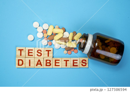 Pills from a container with the text of a diabetes test on wooden cubes. Concept of diabetes or a healthy lifestyle Pills from a container with the text of a diabetes test on wooden cubes. Concept of diabetes or a healthy lifestyle 127386594
