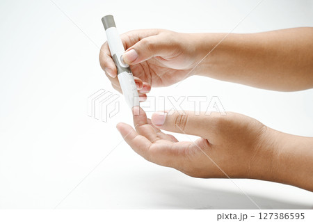 Human hand using a lancet for checking blood sugar level isolated over a white background. Concept of diabetes or a healthy lifestyle Human hand using a lancet for checking blood sugar level isolated over a white background. Concept of diabetes or a healthy lifestyle 127386595