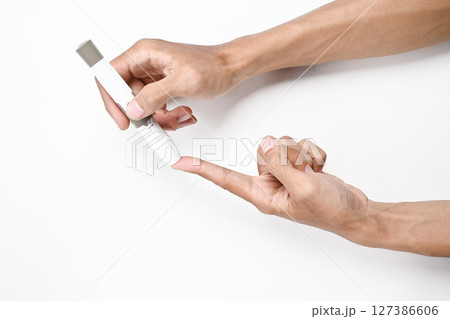 Human hand using a lancet for checking blood sugar level isolated over a white background. Concept of diabetes or a healthy lifestyle Human hand using a lancet for checking blood sugar level isolated over a white background. Concept of diabetes or a healthy lifestyle 127386606