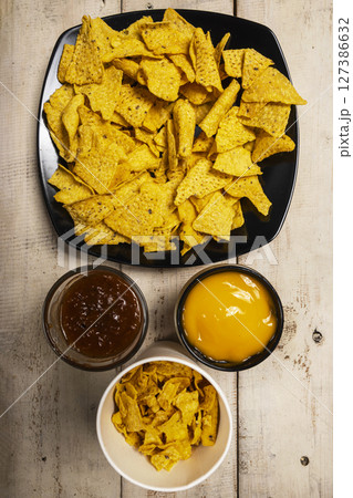 Nachos tortilla chips with cheese and salsa barbecue sauce in a bowl on the table. Food and snacks concept Nachos tortilla chips with cheese and salsa barbecue sauce in a bowl on the table. Food and snacks concept 127386632