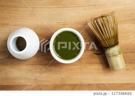 Matcha green tea and a traditional bamboo brush whisk or chasen on a table. Accessories for making matcha green tea. Top view 127386688