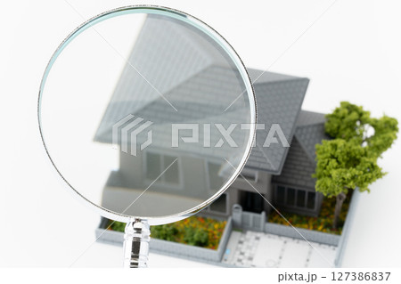 白背景に虫眼鏡とミニチュアの一戸建て住宅 127386837