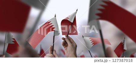 Bahrain flags in their hands on a blurred urban background 127387018