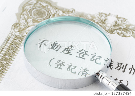 虫眼鏡が置かれた不動産登記識別情報（登記済権利証） 127387454