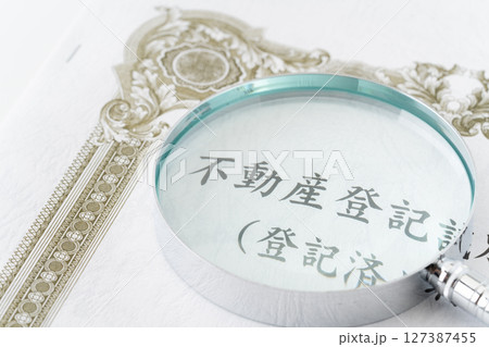 虫眼鏡が置かれた不動産登記識別情報(登記済権利証) 虫眼鏡が置かれた不動産登記識別情報(登記済権利証) 127387455