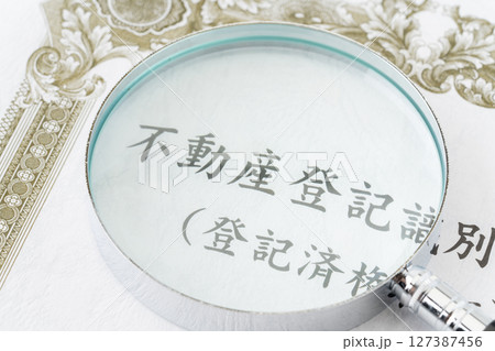 虫眼鏡が置かれた不動産登記識別情報(登記済権利証) 虫眼鏡が置かれた不動産登記識別情報(登記済権利証) 127387456