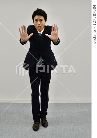 両手で「ストップ」のサインを出す若い男性 127387684