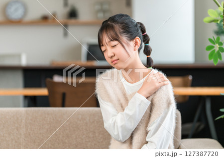 肩凝り,関節痛で肩を抑えて悩む小学生,中学生の女の子 127387720