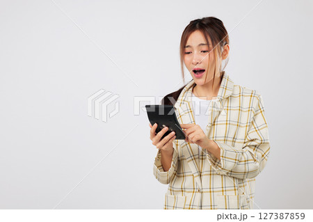 Surprised expression woman checks total on calculator and verifies it again using the same calculator, worried about the financial numbers in her budget plan. isolated studio white background TAX Day Surprised expression woman checks total on calculator and verifies it again using the same calculator, worried about the financial numbers in her budget plan. isolated studio white background TAX Day 127387859