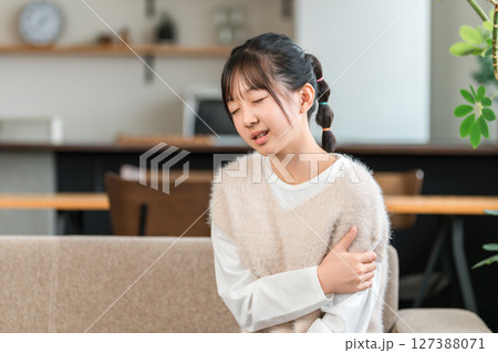 腕が痛くて腕を押さえる小学生,中学生の女の子 127388071
