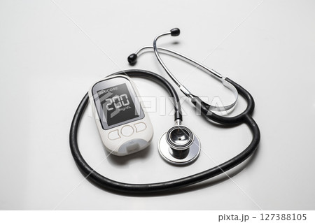 Doctor stethoscope and a glucometer with the glucose level on the screen. Concept of diabetes or a healthy lifestyle 127388105
