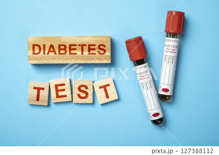 Tube with blood sample for checking blood sugar level with text of diabetes test on wooden cubes. Concept of diabetes or a healthy lifestyle Tube with blood sample for checking blood sugar level with text of diabetes test on wooden cubes. Concept of diabetes or a healthy lifestyle 127388112