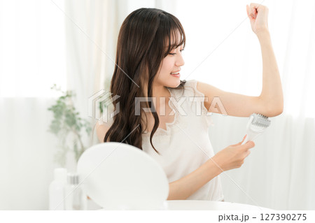 家で腕にマッサージローラーを使う若いアジア人女性 127390275