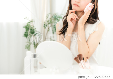 メイク中に鏡を見ながら落ち込む若いアジア人女性（肌荒れ,肌トラブル,ストレス） 127390627